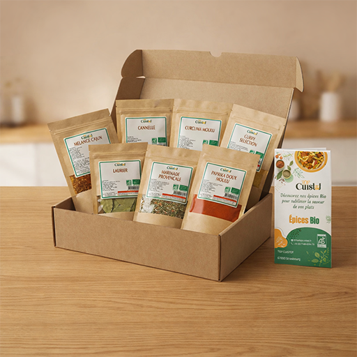 Coffret de 7 épices bio Top Cuistot dans une boîte kraft avec sachets d’épices naturelles et brochure sur table en bois